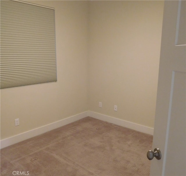 spare room featuring baseboards and light colored carpet