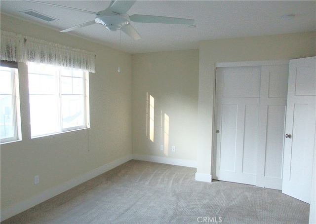 unfurnished bedroom with visible vents, a closet, light carpet, baseboards, and a ceiling fan