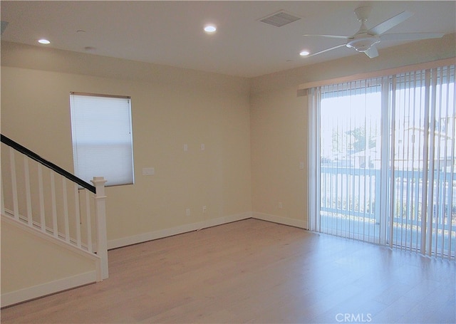 empty room with baseboards, a ceiling fan, light wood finished floors, and visible vents