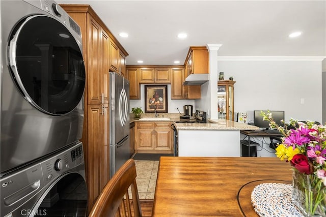 134 S Magnolia Ave Unit 21A, Anaheim, CA 92804 - kitchen with crown molding, stacked washer and clothes dryer, under cabinet range hood, and brown cabinets