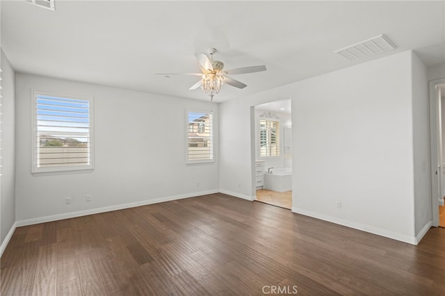 unfurnished bedroom featuring ensuite bath, a ceiling fan, baseboards, wood finished floors, and visible vents