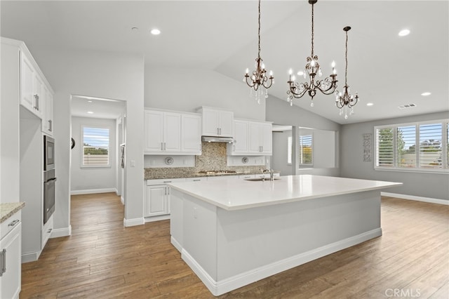 30404 Canyon Point Cir, Menifee, CA 92584 - kitchen with appliances with stainless steel finishes, under cabinet range hood, a chandelier, vaulted ceiling, and tasteful backsplash