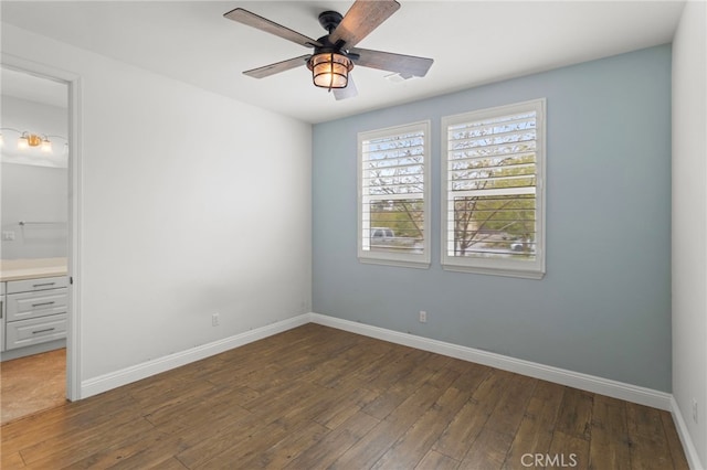 unfurnished bedroom featuring baseboards, ensuite bathroom, wood-type flooring, and ceiling fan