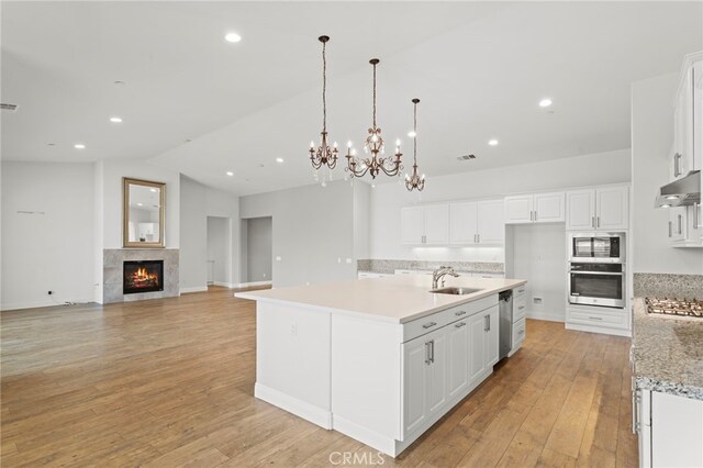 30404 Canyon Point Cir, Menifee, CA 92584 - kitchen with appliances with stainless steel finishes, under cabinet range hood, white cabinetry, a chandelier, and lofted ceiling