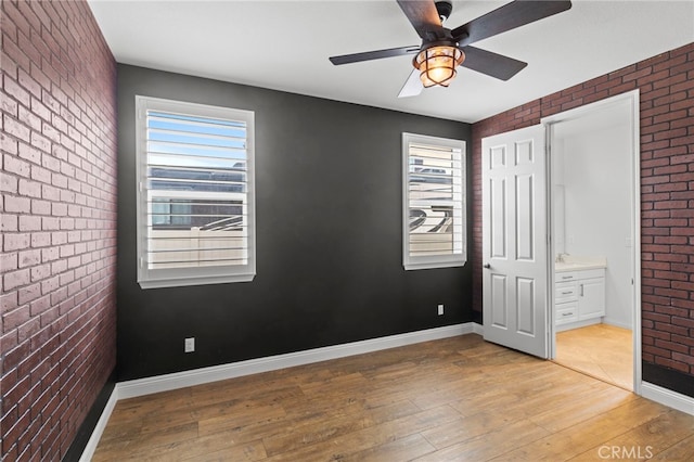 30404 Canyon Point Cir, Menifee, CA 92584 - unfurnished bedroom featuring brick wall, hardwood / wood-style floors, multiple windows, ensuite bath, and a ceiling fan