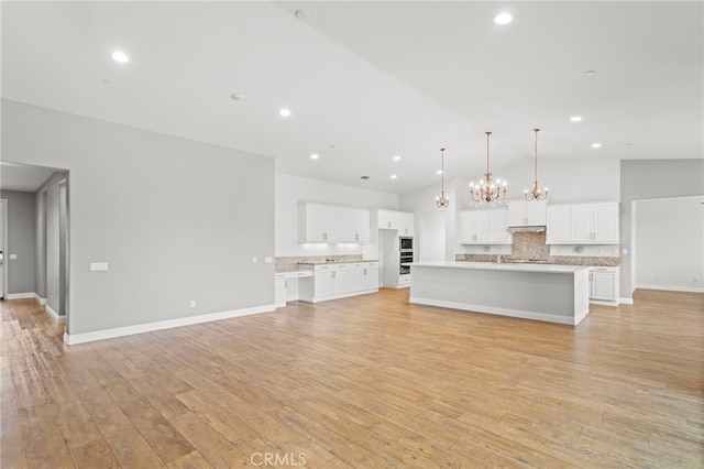 unfurnished living room with recessed lighting, high vaulted ceiling, a notable chandelier, and light wood-type flooring