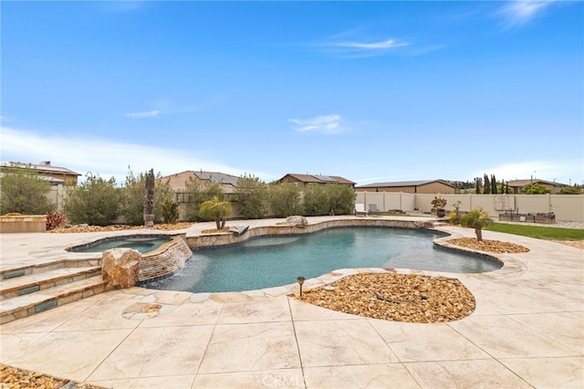 view of pool featuring a fenced backyard, a pool with connected hot tub, and a patio area