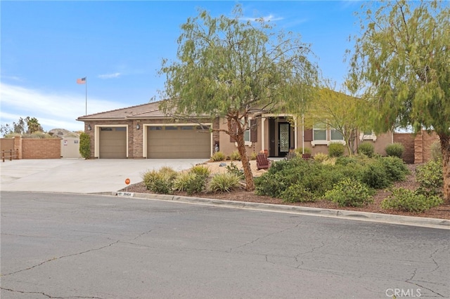 obstructed view of property featuring stucco siding, a garage, fence, and driveway