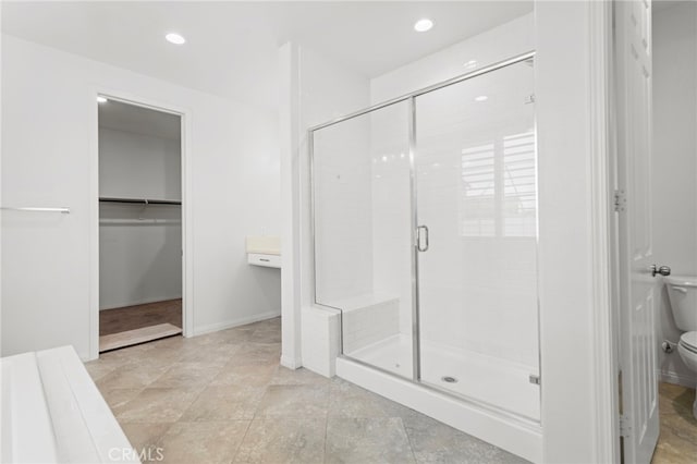 bathroom featuring recessed lighting, a walk in closet, toilet, and a shower stall