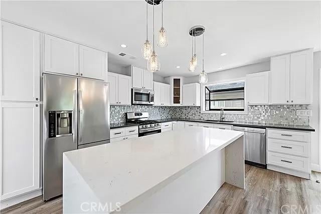 26872 Vista Del Mar, Dana Point, CA 92624 - kitchen with tasteful backsplash, white cabinetry, a sink, stainless steel appliances, and light wood-style flooring