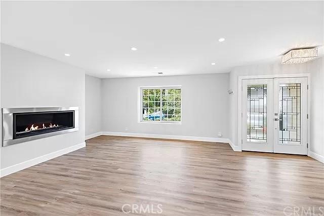 26872 Vista Del Mar, Dana Point, CA 92624 - unfurnished living room featuring french doors, recessed lighting, baseboards, wood finished floors, and a lit fireplace