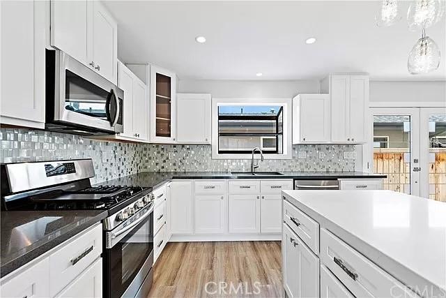 26872 Vista Del Mar, Dana Point, CA 92624 - kitchen featuring appliances with stainless steel finishes, tasteful backsplash, a sink, light wood finished floors, and white cabinetry