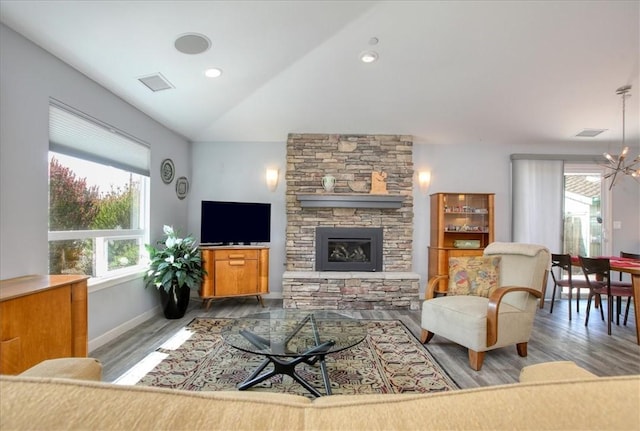 living room featuring visible vents, a fireplace, vaulted ceiling, wood finished floors, and baseboards