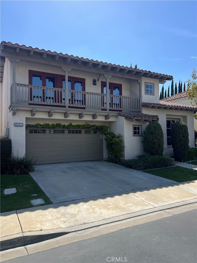 mediterranean / spanish-style home with a balcony, stucco siding, a garage, concrete driveway, and a tiled roof