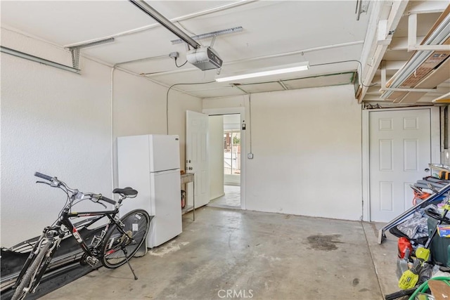 garage with a garage door opener and freestanding refrigerator