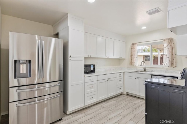 kitchen featuring visible vents, electric range, black microwave, stainless steel refrigerator with ice dispenser, and a sink