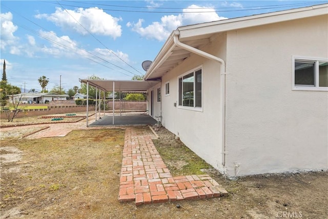 view of property exterior with a patio, fence, and stucco siding