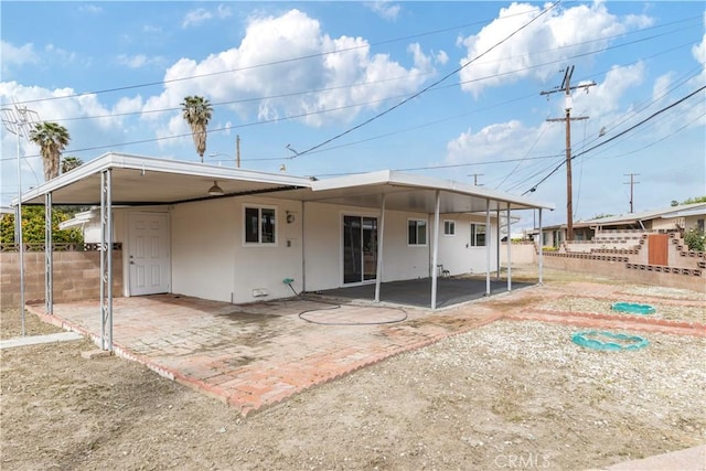 back of house featuring stucco siding, fence, and an attached carport