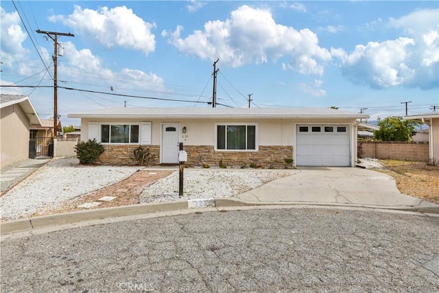 ranch-style house with concrete driveway, fence, stone siding, and a garage