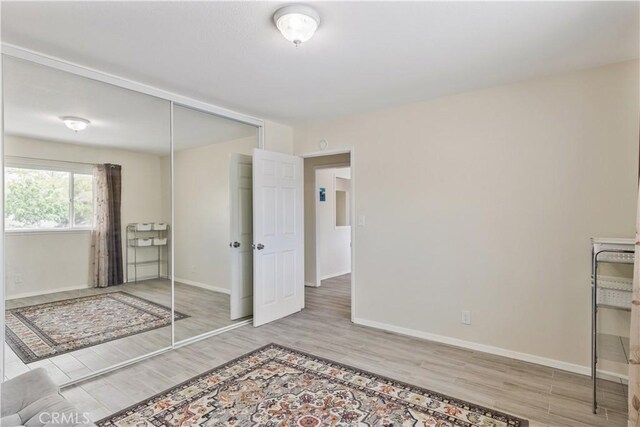 unfurnished bedroom featuring baseboards, wood finished floors, and a closet
