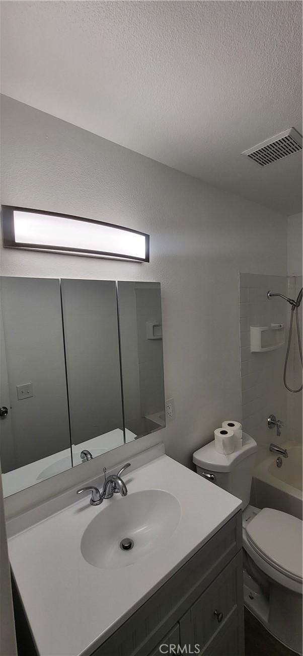 bathroom featuring a textured ceiling, visible vents, vanity, toilet, and bathing tub / shower combination