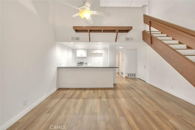 348 S Prospectors Rd Unit 8, Diamond Bar, CA 91765 - unfurnished living room with light wood finished floors, a towering ceiling, stairs, a ceiling fan, and baseboards