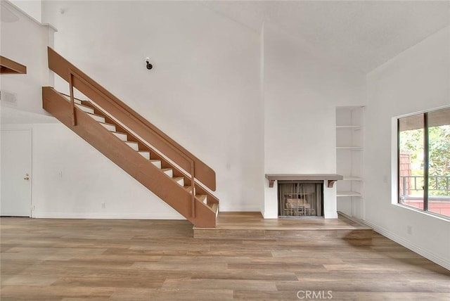 348 S Prospectors Rd Unit 8, Diamond Bar, CA 91765 - unfurnished living room featuring high vaulted ceiling, a fireplace, wood finished floors, stairway, and baseboards
