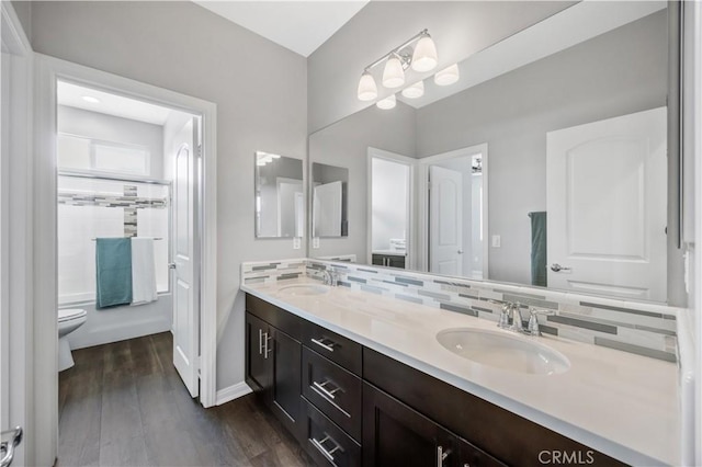 full bath with backsplash, toilet, a sink, and wood finished floors
