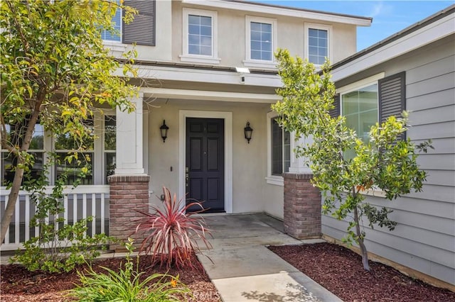 entrance to property with a porch and stucco siding