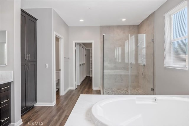 bathroom with a shower stall, wood finished floors, and a garden tub