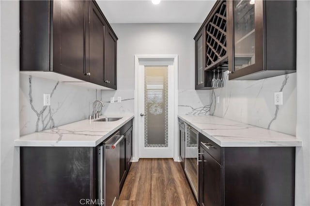 kitchen featuring dark brown cabinetry, dark wood finished floors, decorative backsplash, and a sink