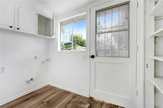 laundry area featuring baseboards, cabinet space, and wood finished floors