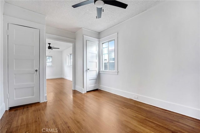 spare room with a ceiling fan, baseboards, wood finished floors, and a textured ceiling