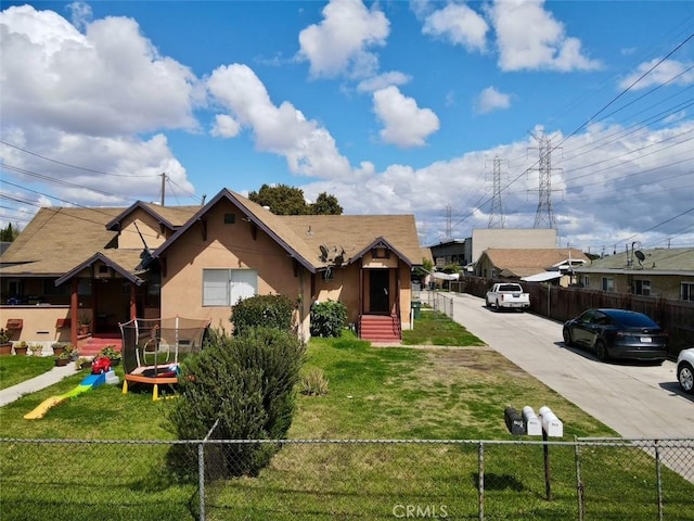 view of front of home with concrete driveway, fence, a front lawn, and stucco siding