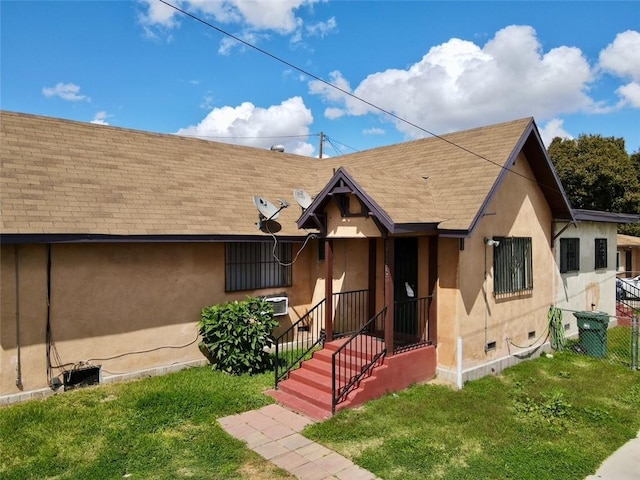 view of front of house featuring roof with shingles, fence, stucco siding, and a front yard