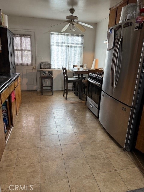 kitchen featuring ceiling fan, appliances with stainless steel finishes, dark countertops, and light tile patterned floors