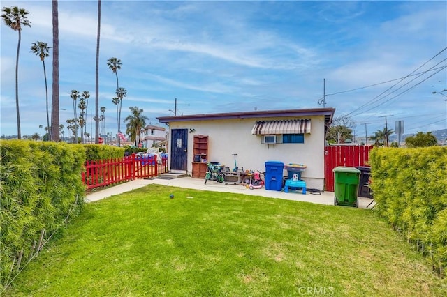 rear view of property featuring a fenced backyard, a patio, stucco siding, and a yard