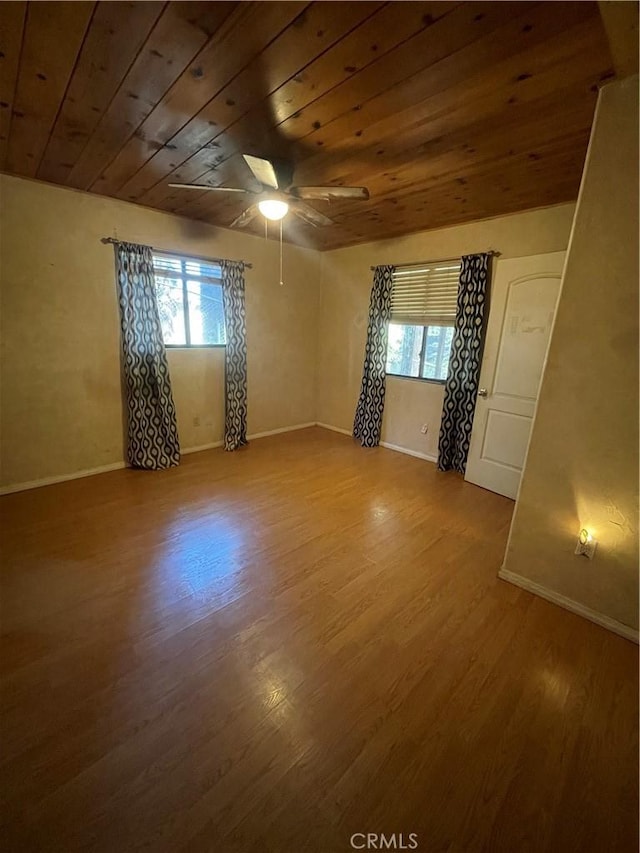empty room featuring a ceiling fan, wood finished floors, and a healthy amount of sunlight