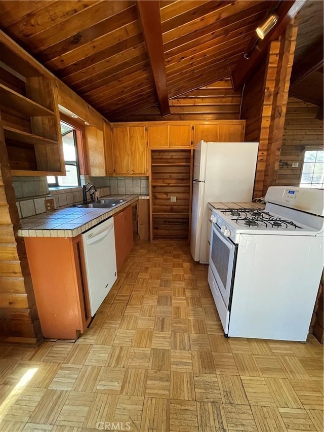 kitchen with a sink, white appliances, tile countertops, vaulted ceiling with beams, and wood ceiling