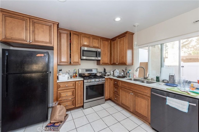 kitchen featuring stainless steel appliances, a sink, brown cabinets, light countertops, and light tile patterned floors
