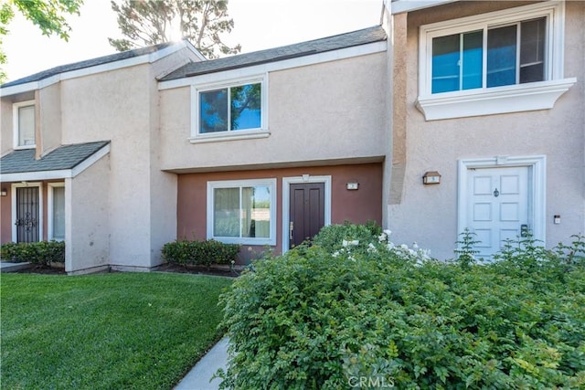 townhome / multi-family property with stucco siding and a front lawn