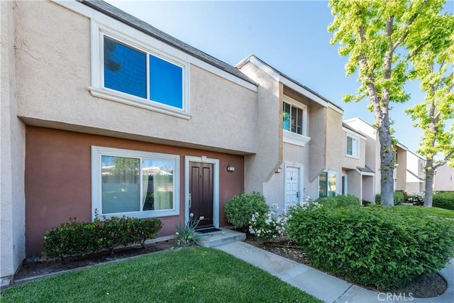 townhome / multi-family property with stucco siding and a front yard
