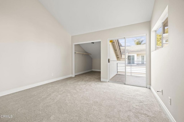 unfurnished bedroom featuring carpet flooring, access to outside, a walk in closet, baseboards, and lofted ceiling