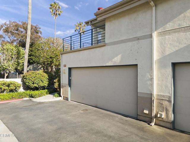 view of side of property featuring a garage, a balcony, and stucco siding