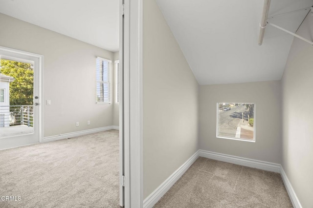 interior space with carpet floors, baseboards, vaulted ceiling, and a wealth of natural light