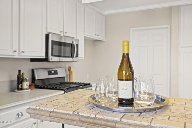 kitchen featuring white cabinetry, tile counters, and appliances with stainless steel finishes