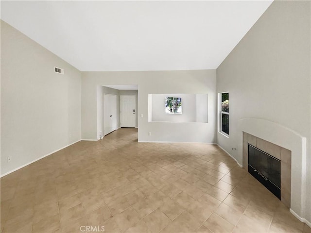 unfurnished living room with visible vents, baseboards, high vaulted ceiling, and a fireplace