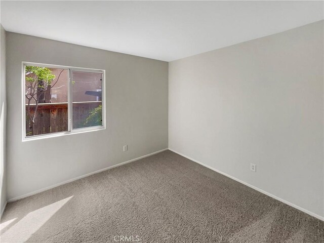 carpeted spare room featuring baseboards