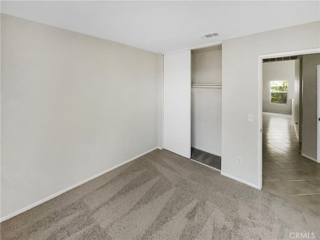 unfurnished bedroom featuring carpet floors, baseboards, visible vents, and a closet