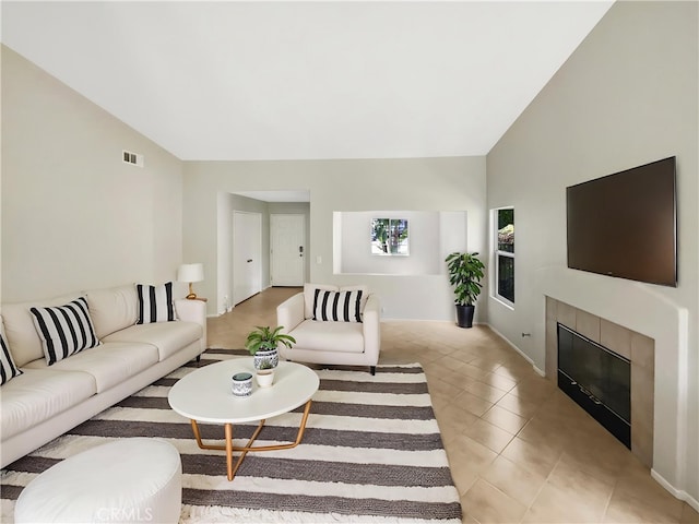 living room featuring high vaulted ceiling, baseboards, a fireplace, and visible vents
